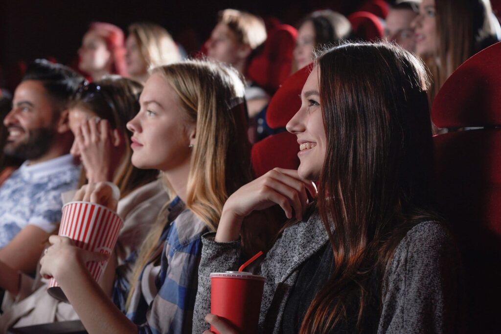 2 filles au cinéma avec des popcorn en train de regarder la vaste comédie de la vie.