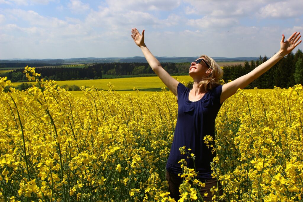 Une femme dans un champ en pleine expression de son affirmation avec gratitude.