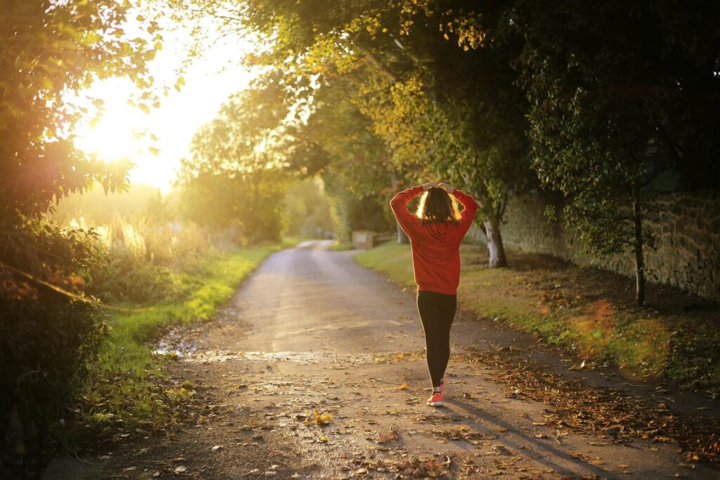 Une femme applique la marche contemplative sur un chemin ensoleillé.
